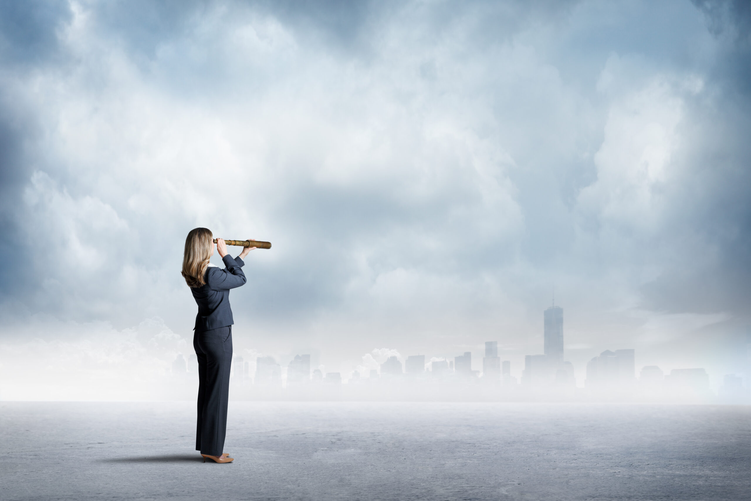 A businesswoman uses a spyglass to look at a city skyline that sits on the distant horizon.
